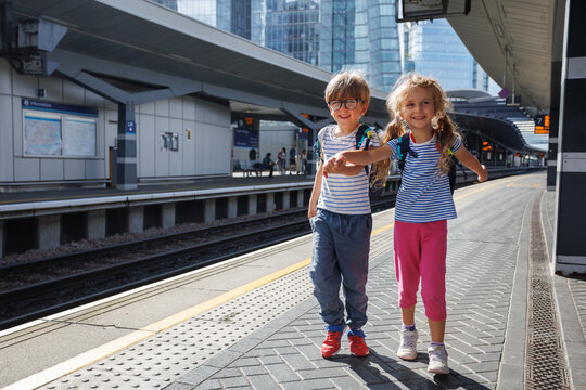Two kids joyfully explore urban station together wait for train