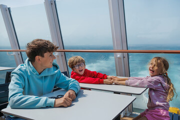 Smiling children tourists sit on a boat deck, with ocean views