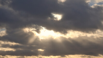 Sunbeams break dramatically through dense clouds in the sky.