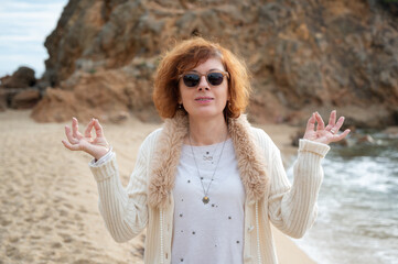 Woman meditating on beach showing mudra hand gesture