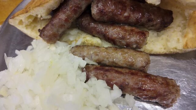 Top-down close-up of cevapi served in lepinja with onions, showcasing a classic Balkan grilled meat dish and appetizing street food look