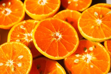 A vibrant, high-angle close-up showcases a rich arrangement of freshly sliced oranges, their vivid, bright orange flesh and textured rinds creating a natural, inviting pattern.