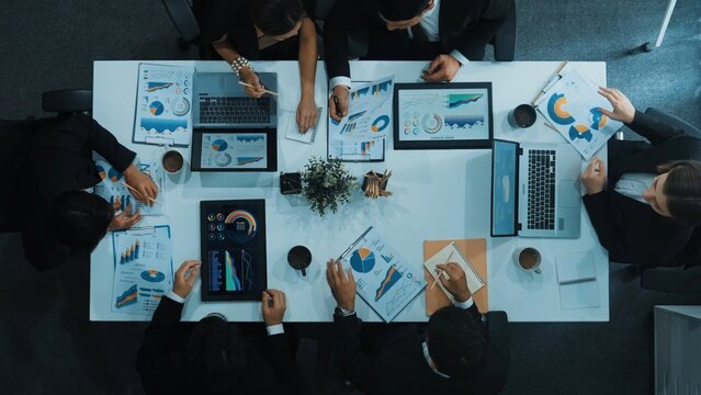 Top down aerial view of business people discussing about financial strategy on table with document and tablet display investment statistic. Time lapse of smart team brainstorm about plan. Directorate.