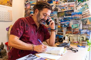 Hispanic man on phone call organizing tourism reservations at his travel agency © Carlos