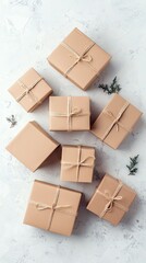 Overhead shot of several wrapped gift boxes with twine on a textured white surface, with greenery.