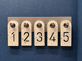 Numbered plastic tags hanging on a metal rack at the entrance to a fitting room in a clothing store, used for organizing customers' items and tracking garments during the try-on process