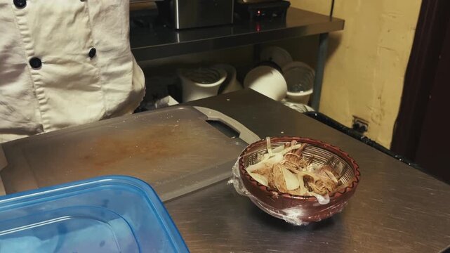 Gloved hands unwrap plastic film from a patterned bowl filled with shredded meat and onions on a metal surface in Miami.