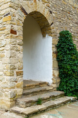 Obraz premium close up of architectural details, old stone wall with arched opening and green ivy