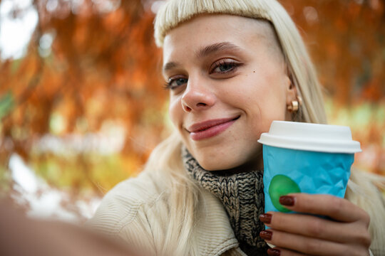 Young woman smiling taking selfie with coffee