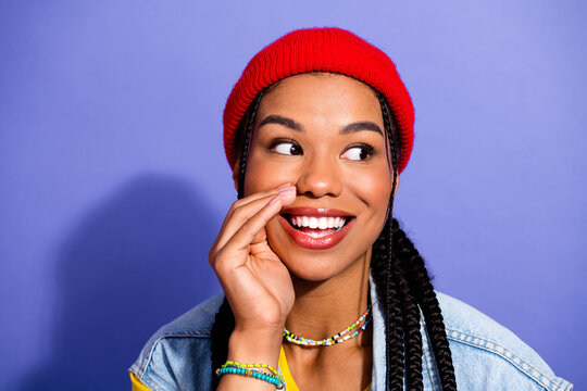 Young stylish woman with red beanie denim jacket and colorful beads smiling against purple background for fashion lifestyle stock photo - Powered by Adobe