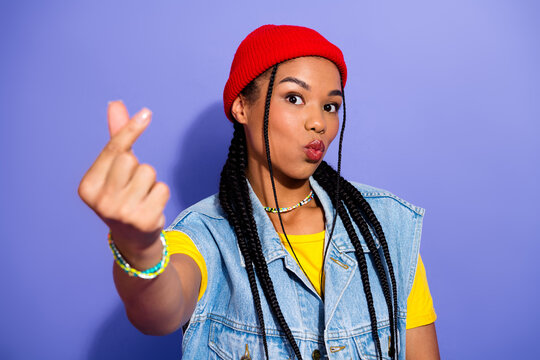 Young woman with braided hair wearing a red beanie denim vest and yellow tee poses playfully purple background hipster streetwear and retro fashion style - Powered by Adobe