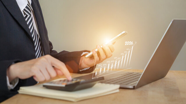 businessman using smart phone and calculator in front of laptop, infographic showing increase arrow graph on bar chart for growth business of year 2026. new opportunity, challenge, strategy, visions