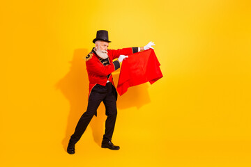 Circus magician on stage performs retro red costume illusionist in bright yellow background