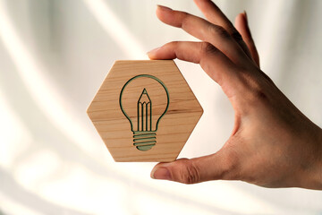 Creative Idea and Innovation Concept with Hand Holding Wooden Hexagon Block Featuring Light Bulb Icon
