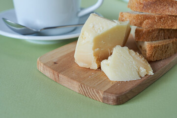 Parmesan cheese on a wooden cutting board and a cup of coffee