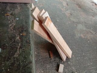 Several cut and shaped wooden components are neatly arranged on the floor of a furniture workshop. This image shows the woodworking process, demonstrating the activity of producing furniture or handic