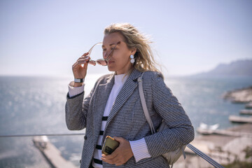 Businesswoman sunglasses ocean view Fashionable woman standing on balcony overlooking sunny sea landscape