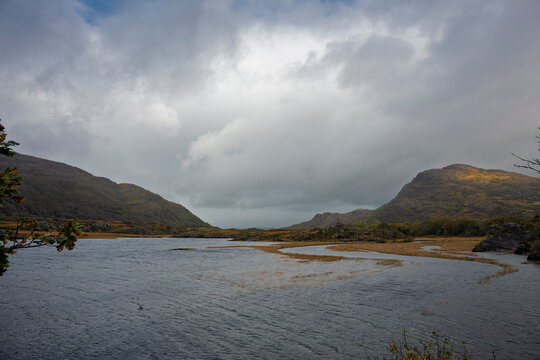 Valley of the Clouds. Autumn view of Owengarriff River widening into a lough, framed by rugged mountains and reflective marshland in Kerry, Ireland