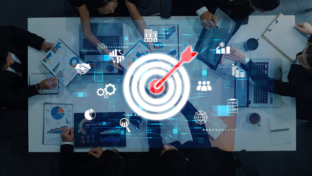 This image captures a diverse team engaged in strategic discussions, highlighting the importance of target focus and data analytics for business growth and collaboration. Trope - Powered by Adobe