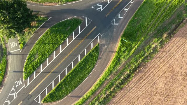 Aerial view of a road intersection with green spaces and field nearby