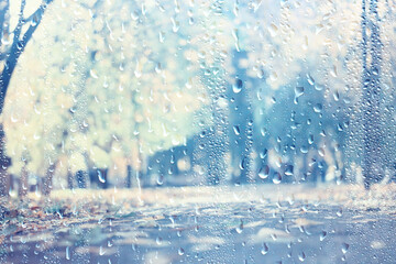 raindrops on glass blurred autumn background trees in the park, seasonal backdrop rainy weather