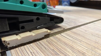 Sanding wooden board with belt sander smoothing surface texture during woodworking process creating fine dust and linear finish close up, taken handheld. High quality 4k footage