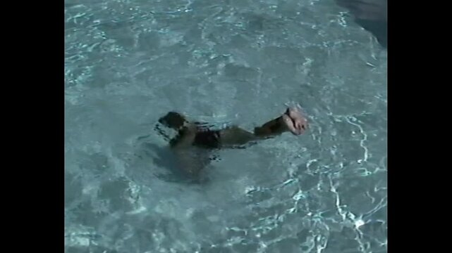 Young child submerged underwater with legs sticking up in a clear swimming pool