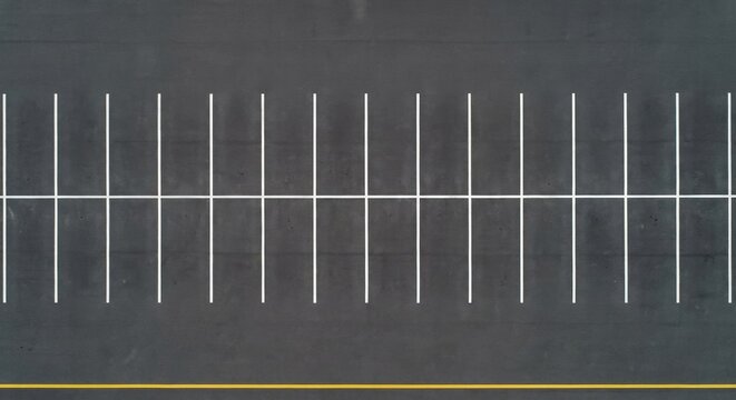 Aerial top down view of empty parking spaces with white and yellow lines