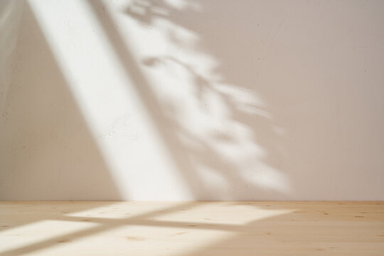 Wooden table mockup on stucco background with window shadow on the wall. Mock up for branding products, presentation and health care.