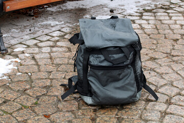 Lost backpack resting on cobblestone street in winter