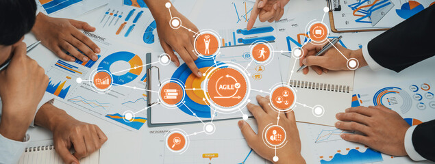 A dynamic business meeting showcasing teamwork and strategy. Participants analyze charts and engage in discussions about agile concepts and project planning. Amity