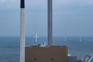 Industry on the sea near Copenhagen contrasts with wind turbines and clean power infrastructure, linking energy and environment, sustainability and climate action through visible contrast