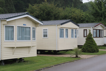 Static caravans lined up on a grassy campsite with trees in the background.