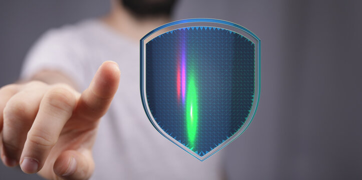 A person's hand pointing at a futuristic digital security shield representing data protection, cyber security, and online safety. Ide