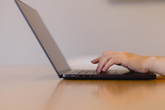 hand typing on a laptop keyboard on a wooden desk, representing remote work, digital lifestyle, freelance productivity modern business communication.