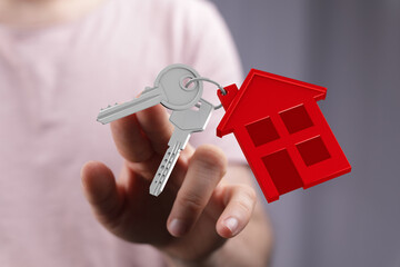 Hand holding house keys with red house keychain, symbolizing homeownership, real estate, and the dream of owning a home. Ideal for property, mor © vegefox.com