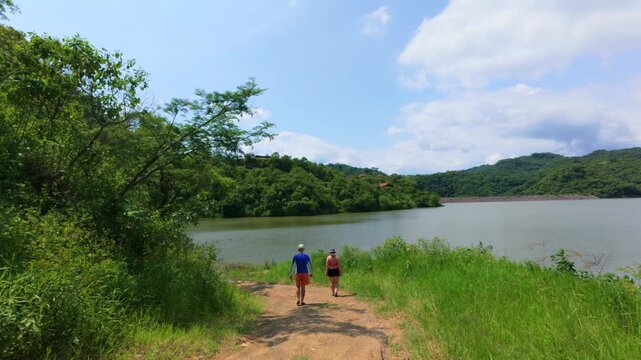 Two hikers walking near El Carrizo reservoir (Presa El Carrizo) under cloudy spring sky