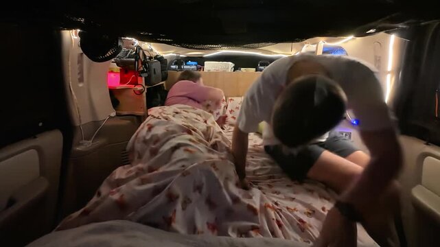 Couple getting ready for bed inside a cozy camper van setup with LED lights
