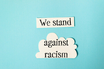 Paper cutouts with message promoting unity and standing against racism on blue background