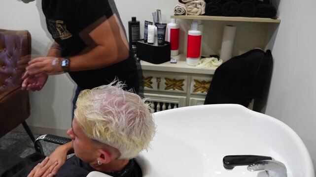 Hairdresser inspecting client&rsquo;s scalp for burns or damage prior to continuing bleaching treatment