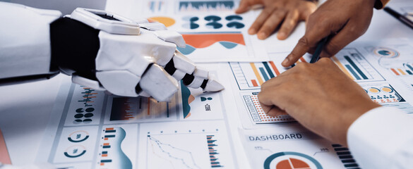 A robot hand and human hands engage in a collaborative analysis of various data charts and dashboards during a strategic business meeting.Noogenesis