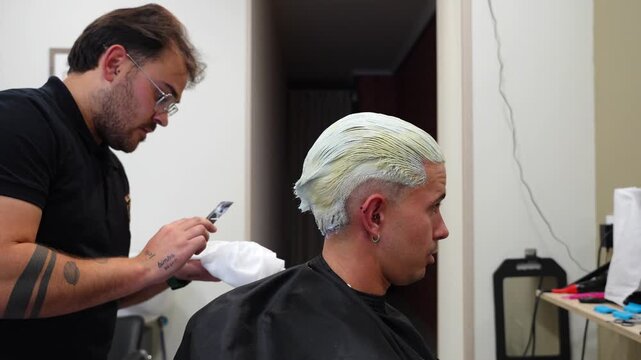 Hairdresser using a comb to remove the first bleach layer while protecting fragile hair from breakage