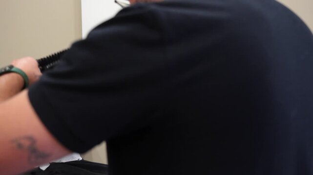 Close up shot of a cheerful barber using a trimmer and smiling during haircut service