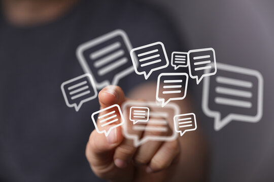 Close up of a hand interacting with digital speech bubble icons, representing online communication and messaging. - Powered by Adobe