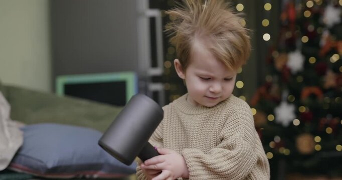 A little boy blow-dries his hair at home, slow motion