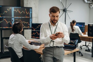 Boss is standing in front of workers. Business people are working with stock market exchange in office