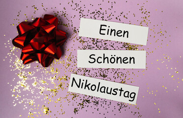 Red gift bow with festive greeting cards and glitter on a purple background for holiday celebration