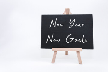 New Year goals written on a blackboard with wooden easel, symbolizing fresh beginnings and aspirations