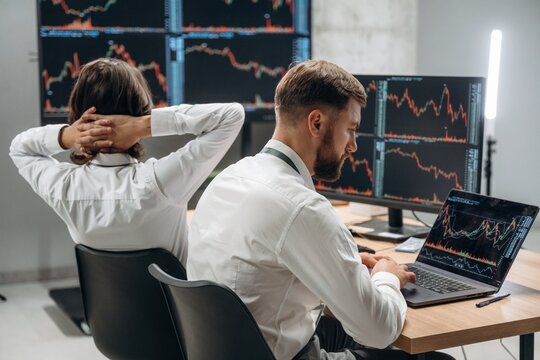 Focused at work, analyzing the data. Two male exchange workers are in the office together