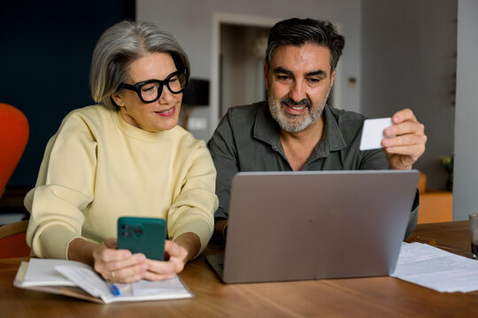 Mature couple making online payment smiling and shopping online